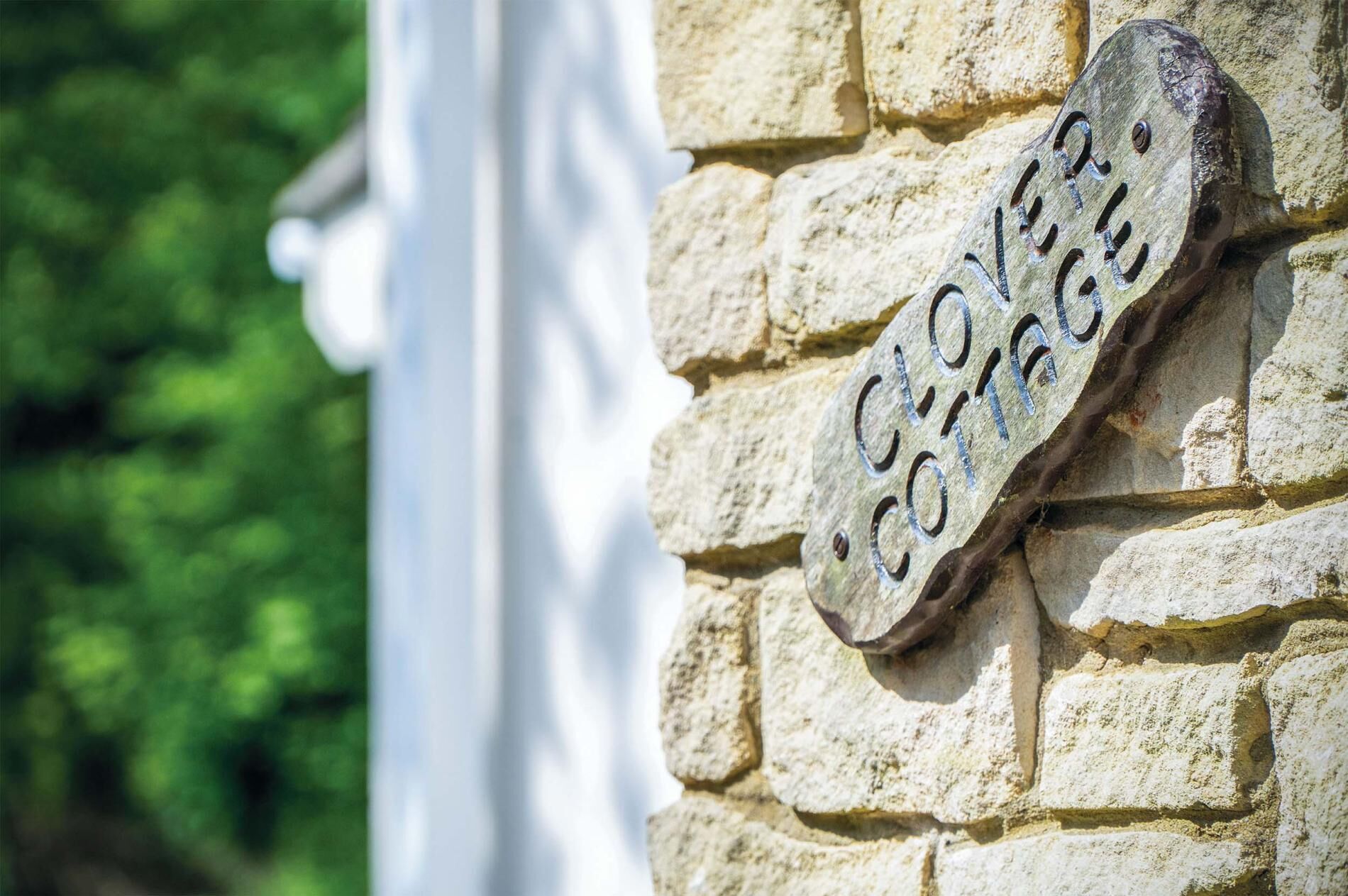A stone wall with a metal sign that reads "CLOVER COFFEE".