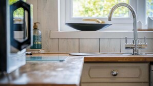 A kitchen with a modern faucet, a bowl sink, and a wooden countertop. - Clover Cottage - 2 Bedroom Cottage - Begelly (Kilgetty)