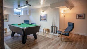 Een pooltafel met een blauwe stoel en een lamp.
