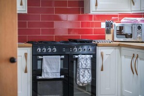 Eine Küche mit roter Fliesenrückwand, einem schwarzen Herd und einer Mikrowelle auf der Arbeitsplatte.