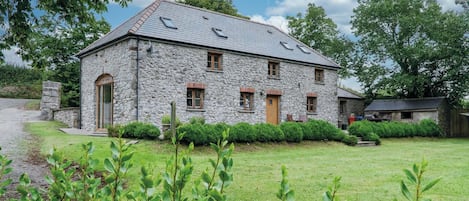 A stone house with a sloped roof, multiple windows, and a well-maintained lawn.