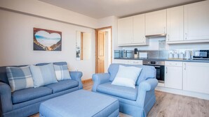 A modern living room with a sofa set and a kitchen area. - Harbour Hideaway - 1 Bedroom Apartment - Saundersfoot (Saundersfoot)