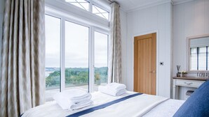 Et hotelværelse med en stor seng, en trædør, et badeværelse med et spejl og udsigt til det fri.