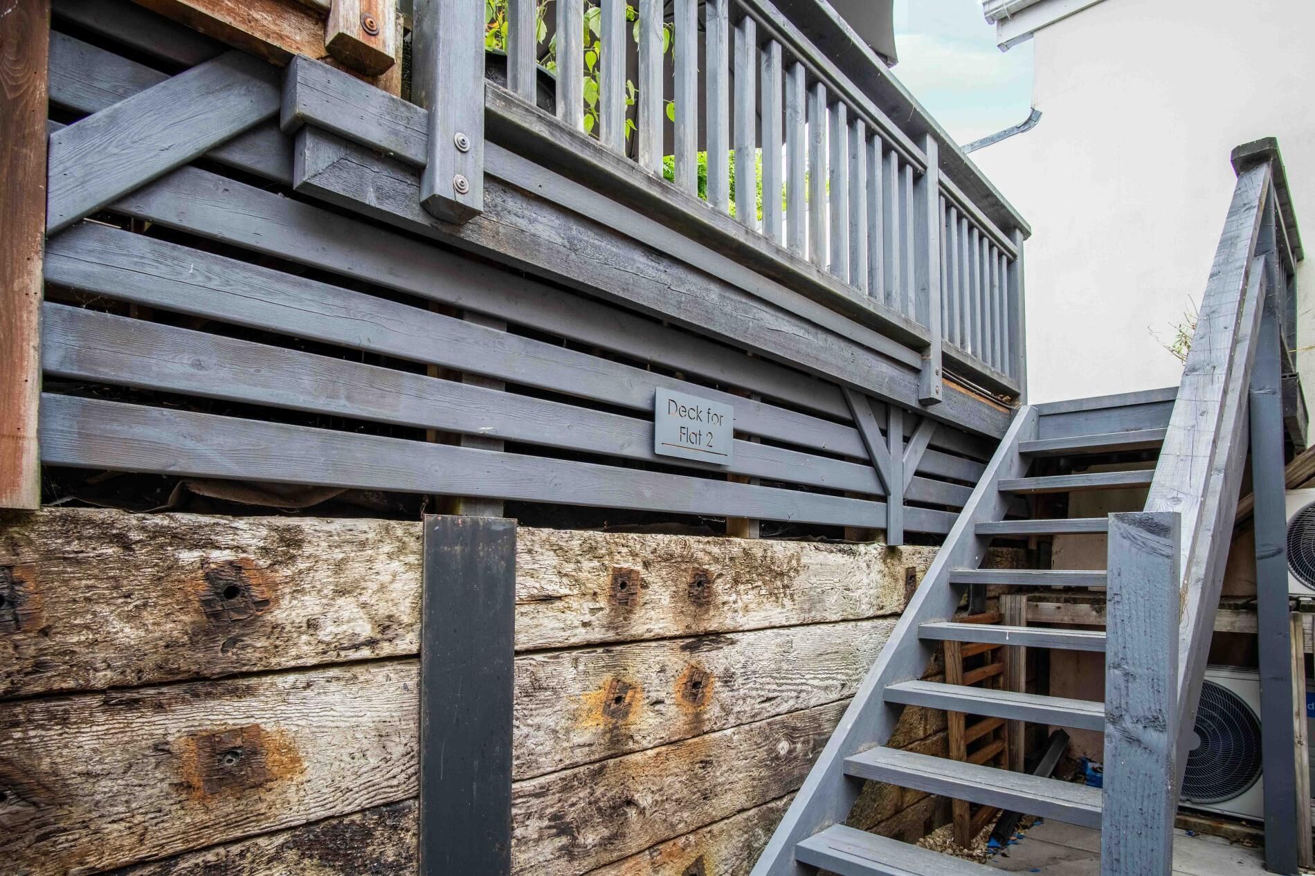 A wooden deck with a sign indicating 'Deck for Flat 2'.