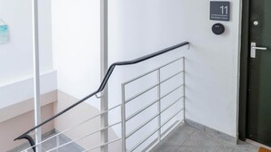A staircase with a metal handrail, a door labeled "11 Beddoes Court", and a small sign with "eSafe" on it.