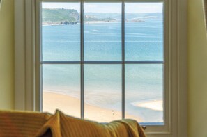 A window with a view of a beach and cliffs.