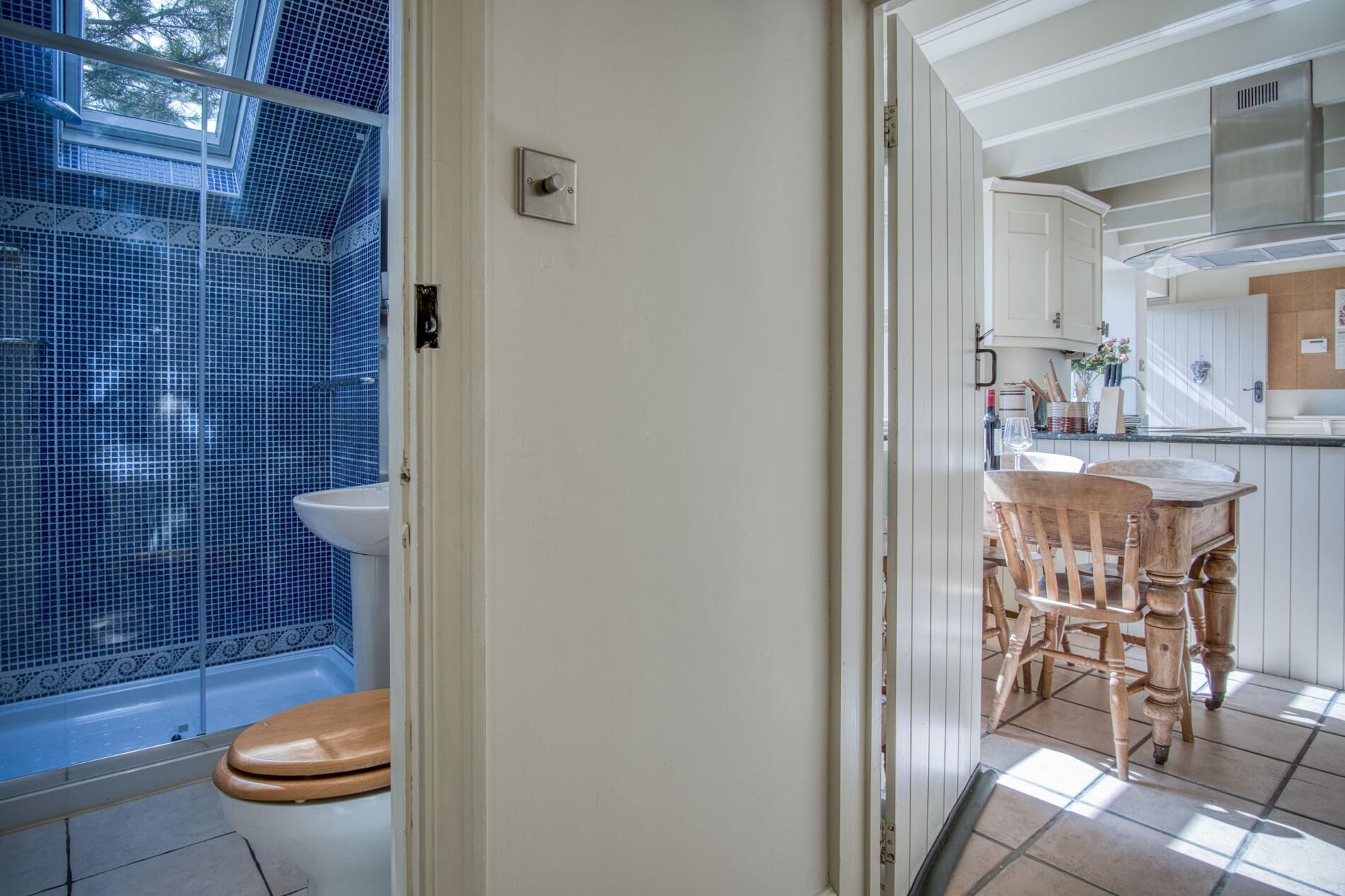 Une salle de bain avec des toilettes, une douche et un lavabo. Une chaise en bois et une table se trouvent dans la pièce adjacente.