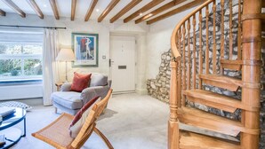 A cozy living room with a wooden staircase, a comfortable sofa, and a wicker chair. - Fern Cottage - 2 Bedroom Cottage - St Florence (Tenby)