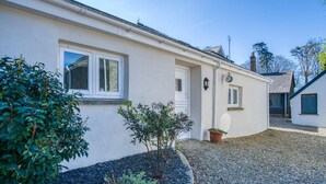 A single-story building with a white exterior, a small porch, and a gravel driveway. - The Studio - 1 Bedroom Cottage - Princes Gate (Narberth)