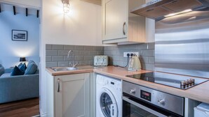 A compact kitchen with a washing machine, oven, and toaster.