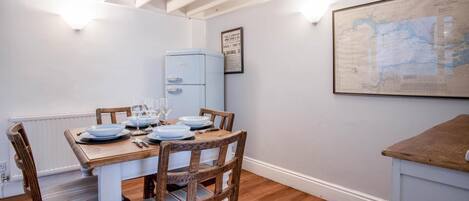 A dining area with a wooden table set for four, a vintage blue refrigerator, and a map on the wall.