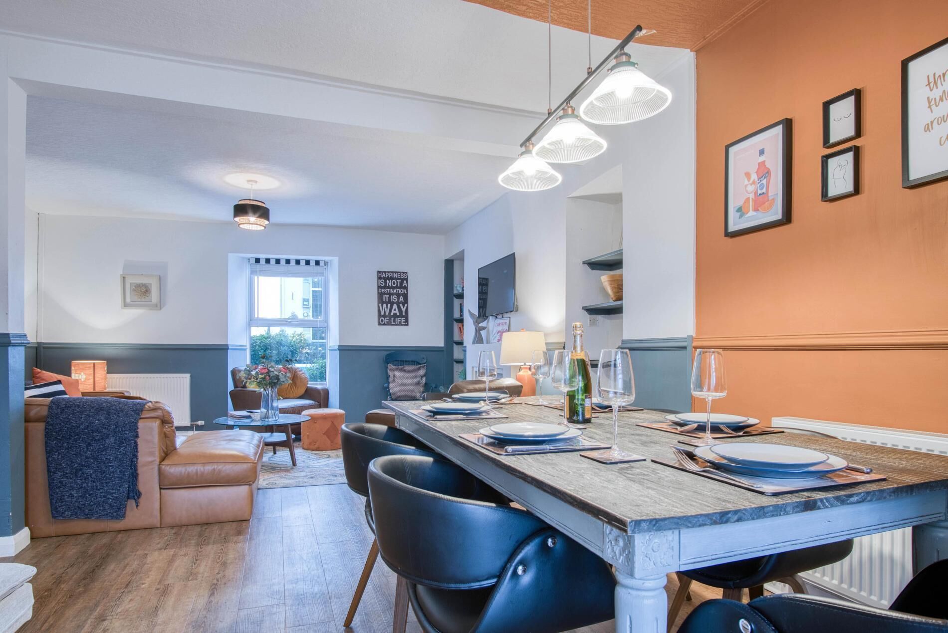 A dining area with a wooden table set for six, surrounded by blue chairs.