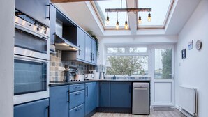 Een moderne keuken met blauwe kastjes, een vaatwasser en een dakraam.