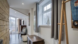 A hallway with a wooden floor, a wooden bench, a chair, and a painting on the wall. - Beachwood - 2 Bedroom Cottage - Penally (Tenby)