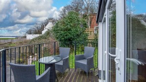 A balcony with wicker furniture and a glass door. - Beachwood - 2 Bedroom Cottage - Penally (Tenby)