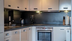 Una cocina moderna con electrodomésticos de acero inoxidable, incluyendo un horno y un refrigerador, y una encimera negra.