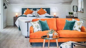 A modern bedroom with a large bed, an orange sofa, and a glass coffee table. - The Pig Sty - 1 Bedroom Studio - Princes Gate (Narberth)