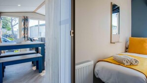 Habitación de hotel con cama, mesita de noche, una silla, ventana con cortinas y vistas al exterior.
