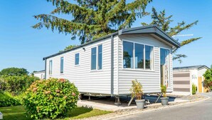 Una casa móvil de un nivel con techo plano, ventanas amplias y un pequeño porche.