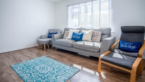 Una sala moderna con un sofá gris, un sillón a juego y una alfombra estampada.
