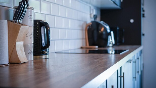 Una encimera de cocina con una cafetera, un juego de cuchillos y un dispensador de toallas de papel.