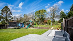 Un patio trasero con un trampolín, una casita de juegos y un tobogán.