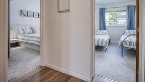 Un dormitorio con dos camas, una ventana con cortinas, un ventilador de techo y una obra de arte en la pared.