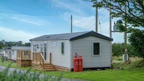 A single-story mobile home with a small deck and a gas cylinder outside.