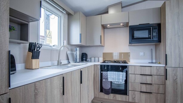 A modern kitchen with wooden cabinets, a built-in microwave, a sink, and a dishwasher.