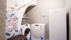 A compact laundry area with a washing machine, dryer, and a refrigerator. - The Lanterns - 9 Bedroom - Sleeps 17 - Saundersfoot Village Centre (Saundersfoot)