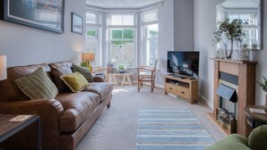 Un salon chaleureux avec un canapé en cuir, une table basse en bois, un meuble pour la télévision et une cheminée.