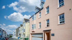 A row of terraced houses with a garage door, a street, and parked cars.