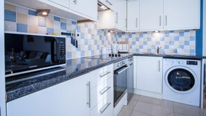 A modern kitchen with white cabinets, a microwave, a stove, and a washing machine.