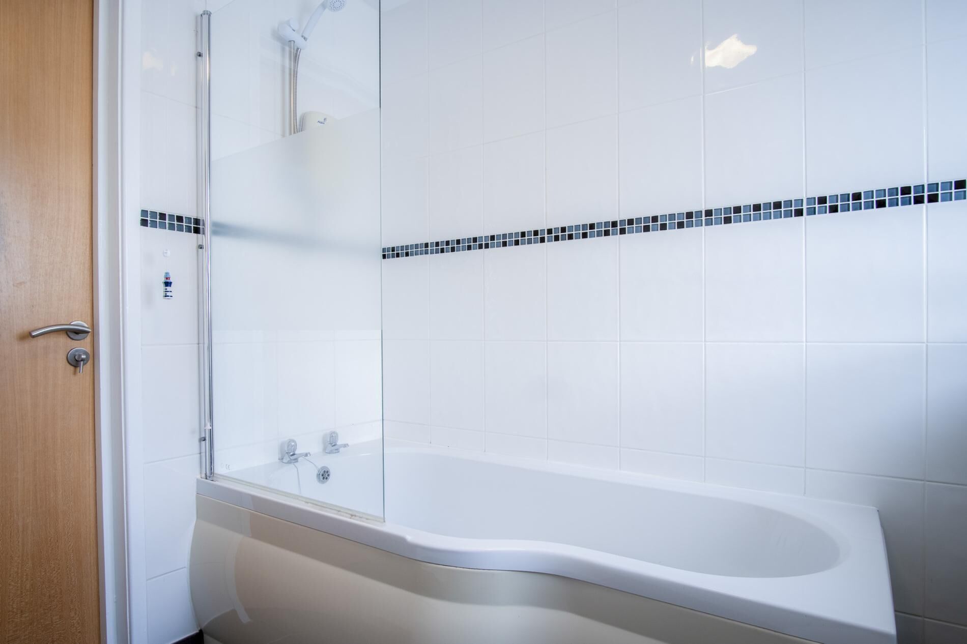 A modern bathroom with a white bathtub, a glass shower enclosure, and a tiled shower area.