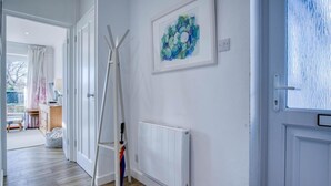 Een gang met een radiator, een witte deur en een raam met vorst.