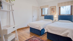 A bedroom with two beds, a desk, a chair, a potted plant, and a window with a view. - Marina House Annex - 1 Bedroom - Neyland (Milford Haven)