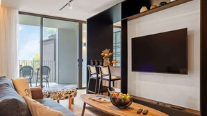 A modern living room with a sofa, coffee table, and a flat-screen TV mounted on the wall. - Luxury 5-Star Stay at Savoy Insular (Funchal)