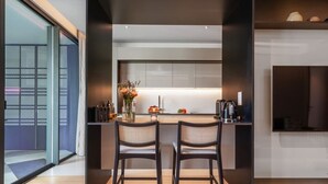 A modern kitchen with a central island, two bar stools, and a large window with a view of a building. - Luxury 5-Star Stay at Savoy Insular (Funchal)