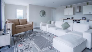 A modern living room with a beige sofa, a white sofa, and a patterned rug. - Ridgeway Retreat - 1 Bedroom Cottage - Manorbier (Tenby)