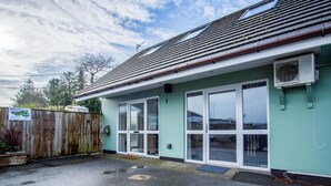 A single-story building with a green exterior and a sloped roof. - Ridgeway Retreat - 1 Bedroom Cottage - Manorbier (Tenby)