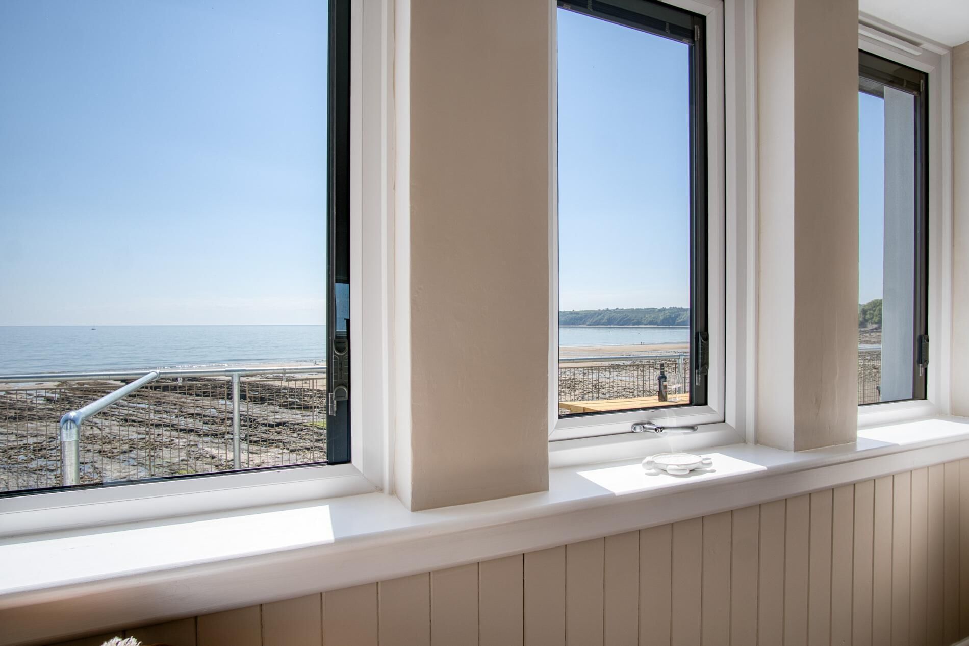 A room with a view of the beach and sea through large windows.