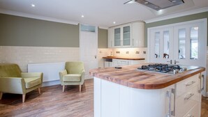 A modern kitchen with a central island, white cabinetry, and a wooden countertop. - Ridgeway Meadow Bungalow - 3 Bedroom - Manorbier (Tenby)