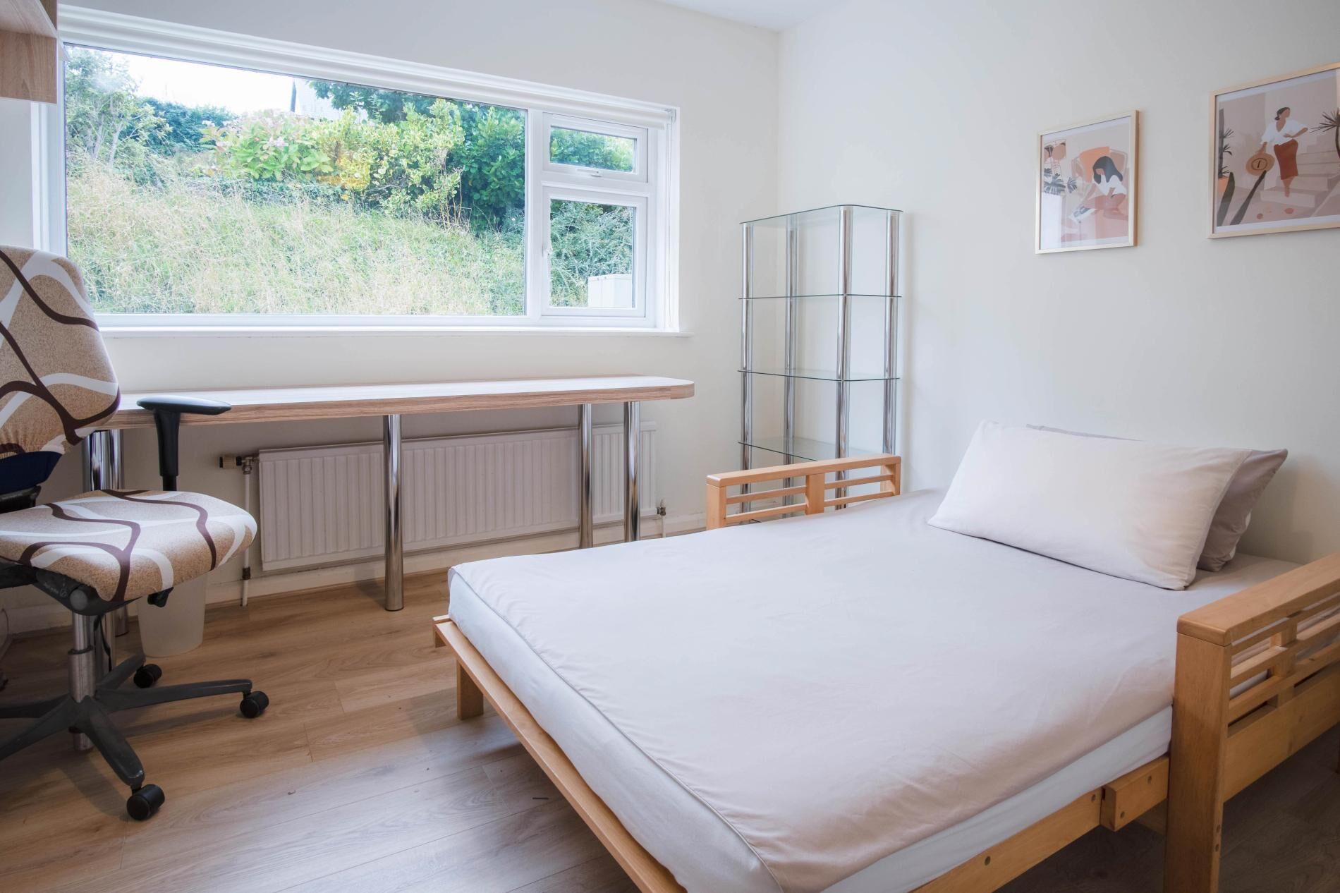 Een slaapkamer met een bed, een bureau en een stoel.