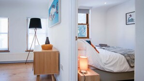 A bedroom with a bed, bedside table, lamp, and a painting on the wall.