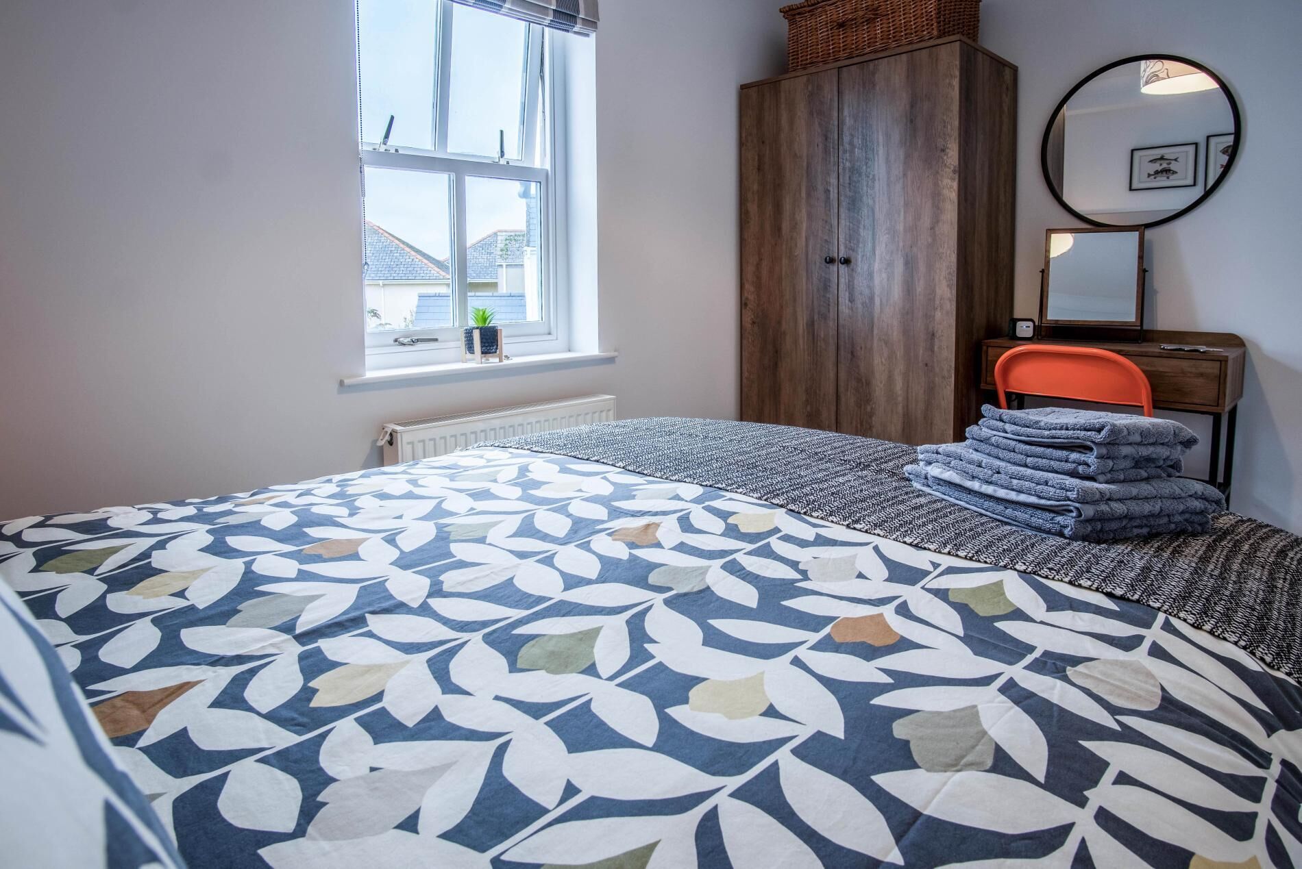 A bedroom with a bed, a wardrobe, a window, and a mirror.