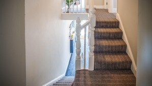 Una escalera con alfombra estampada y barandilla blanca.