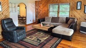 Ein gemütliches Holzhaus-Interieur mit einer Eckcouch, einem Liegesessel und einem Couchtisch.