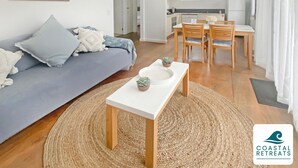 En moderne stue med sofa, sofabord og spiseområde med stole og bord.