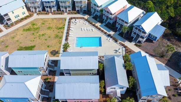 A resort with multiple buildings, a central swimming pool, and a landscaped area with lounge chairs. - Seabbatical | Pet-Friendly Cottage | Screened Decks + Community Pools 🐾 (Port St. Joe)