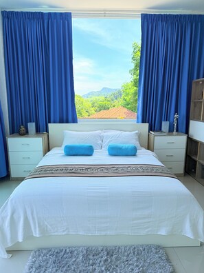 A bedroom with a large bed, white bedding, and blue curtains. - Sea View Luxury Mansion • Pool & Jacuzzi (Koh Chang)